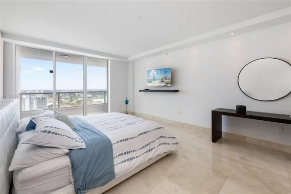 a bedroom with a bed a lamp and large window