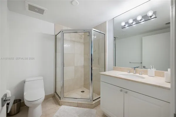 a bathroom with a shower sink vanity mirror and toilet