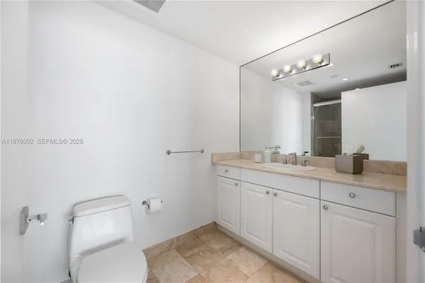 a bathroom with a granite countertop sink a toilet and a mirror