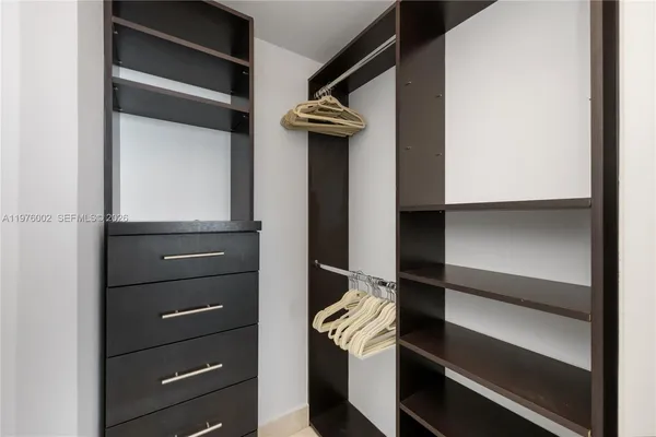 a view of walk in closet with clothes and shoes