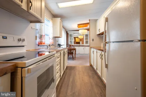 a kitchen with stainless steel appliances a refrigerator a stove a sink and a refrigerator with wooden floor