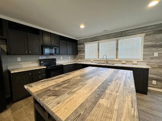 a kitchen with granite countertop wooden cabinets a stove top oven a sink and dishwasher