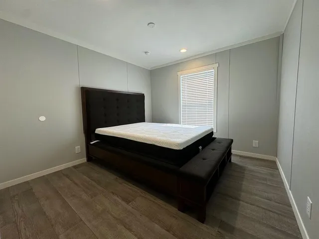 a bed sitting in a spacious bedroom next to a window
