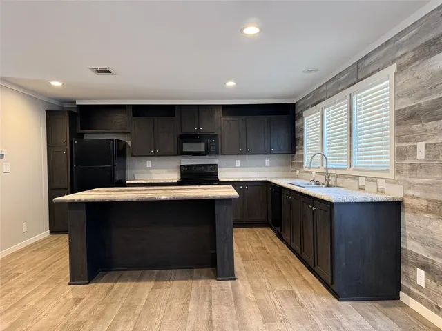 a kitchen with stainless steel appliances granite countertop a sink a stove a refrigerator and a microwave