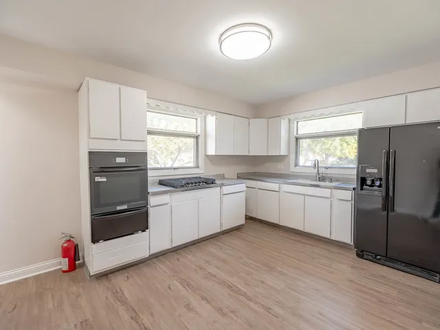 a kitchen with granite countertop a refrigerator and white cabinets