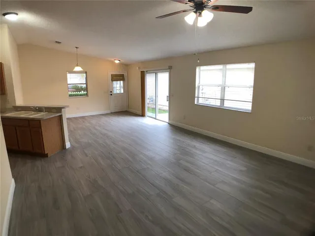 a view of an empty room with window and wooden floor