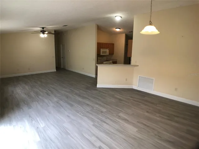a view of a room with wooden floor and a ceiling fan