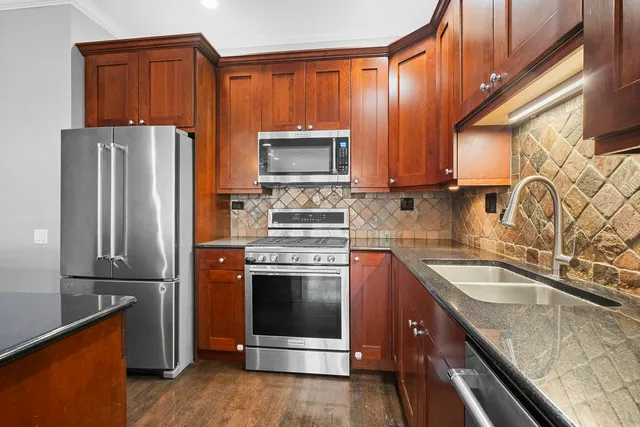 a kitchen with granite countertop a refrigerator stove and sink