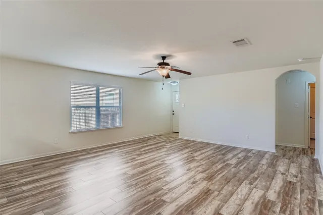 a view of a room with a ceiling fan window and hardwood floor