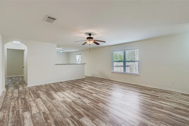 a view of empty room with wooden floor and fan