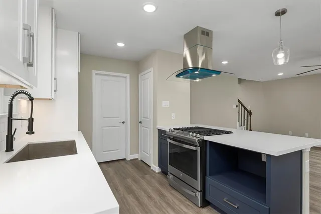 a kitchen with a stove a chandelier and wooden floor