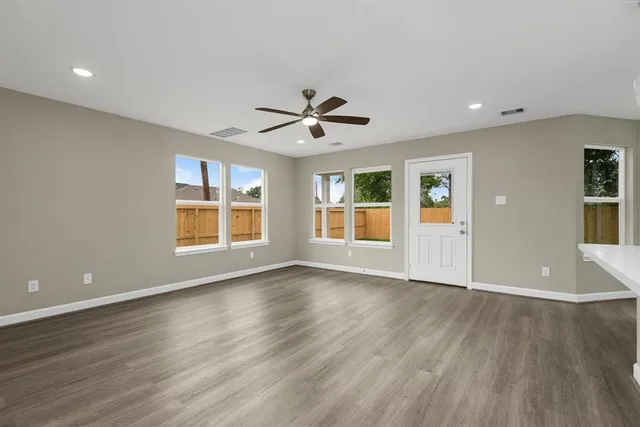 an empty room with wooden floor and chandelier fan