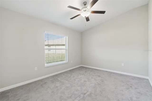 an empty room with chandelier fan and windows