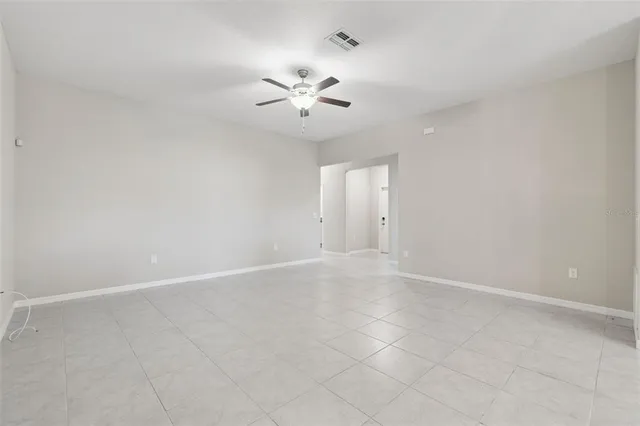 an empty room with a chandelier fan and windows