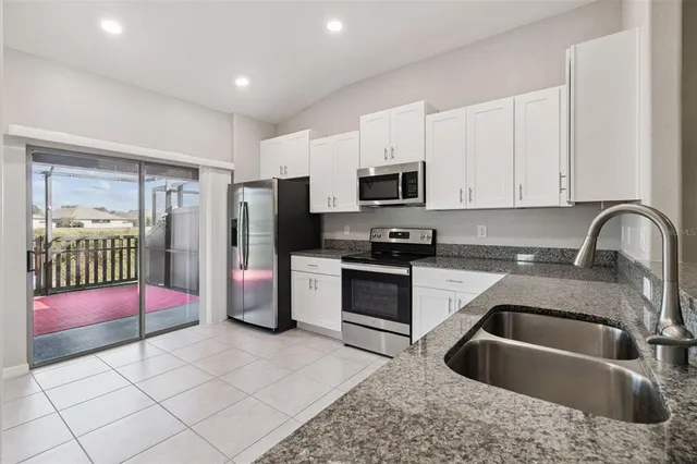 a kitchen with stainless steel appliances granite countertop a refrigerator sink and white cabinets