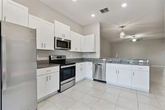 a kitchen with stainless steel appliances granite countertop a stove top oven a sink dishwasher and a microwave