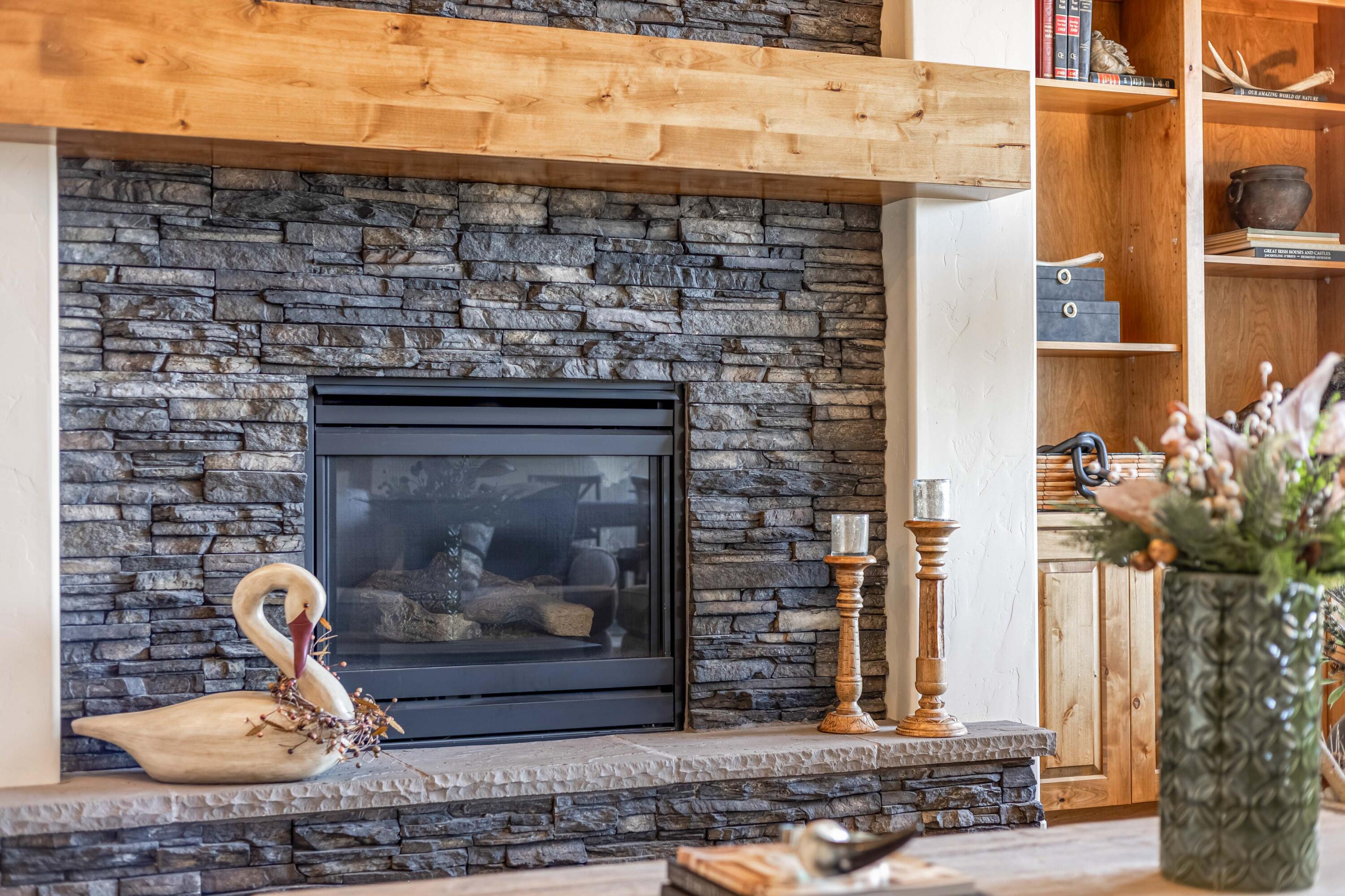 Stone surround gas fireplace with wood mantle.
