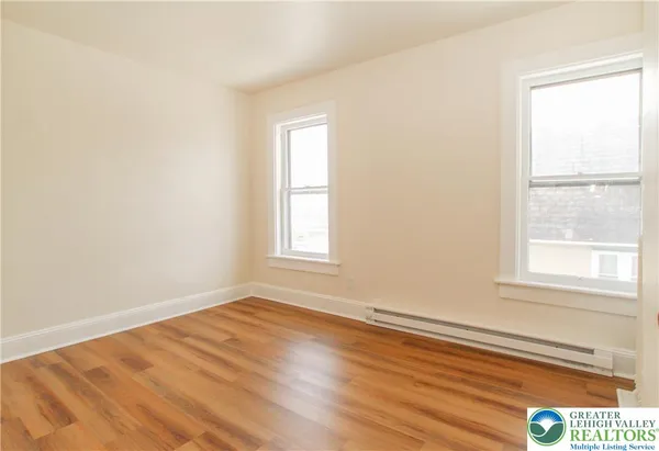 an empty room with wooden floor and windows
