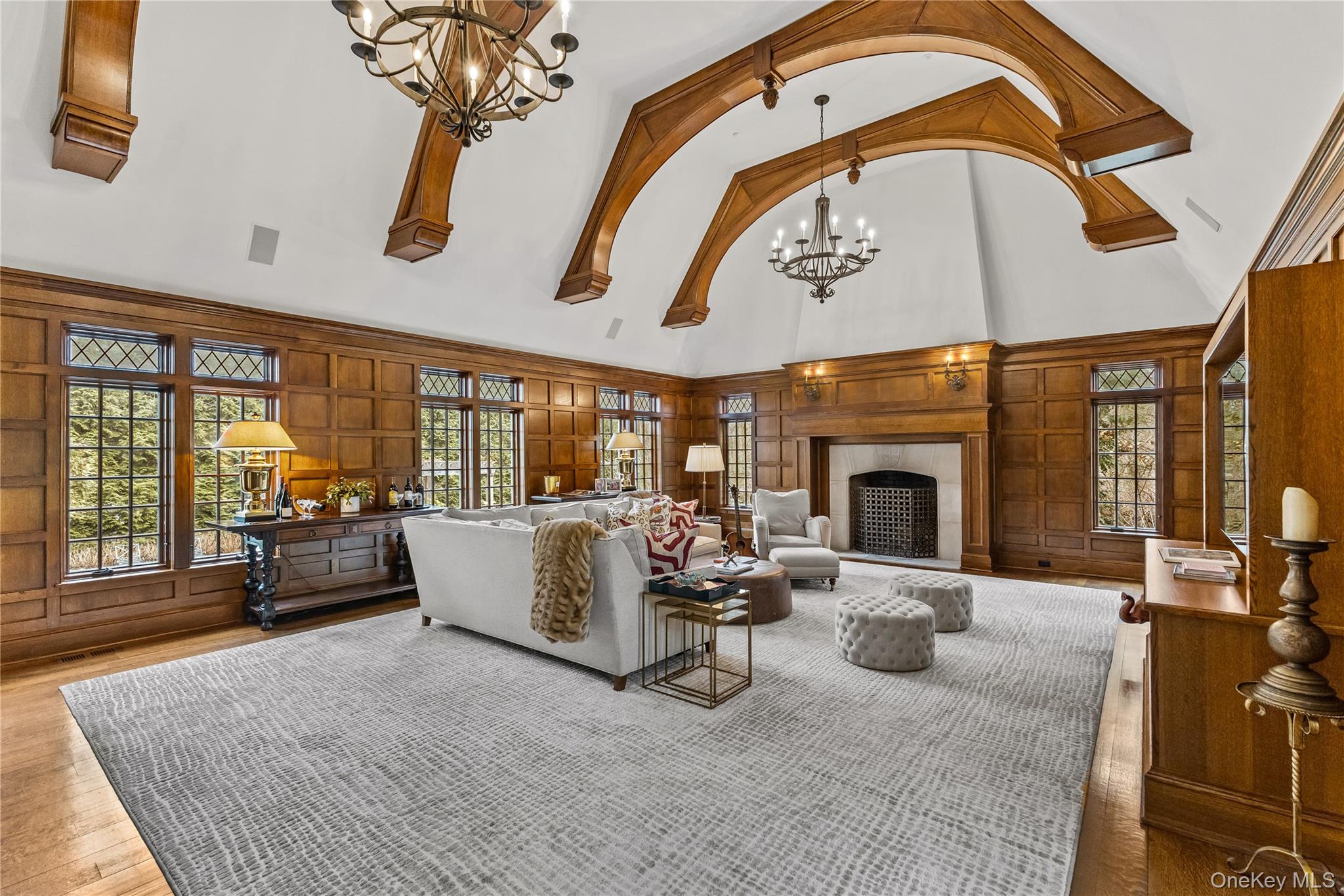 19 Park Drive South Rye, NY 10580 - Photo 18 of 42 Grand family room featuring soaring vaulted ceilings with striking wood beams and rich paneled walls. A stately fireplace anchors the space, creating a warm and inviting setting for relaxing or entertaining.
