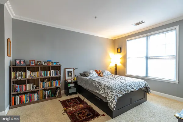a bedroom with a bed book shelf and a window