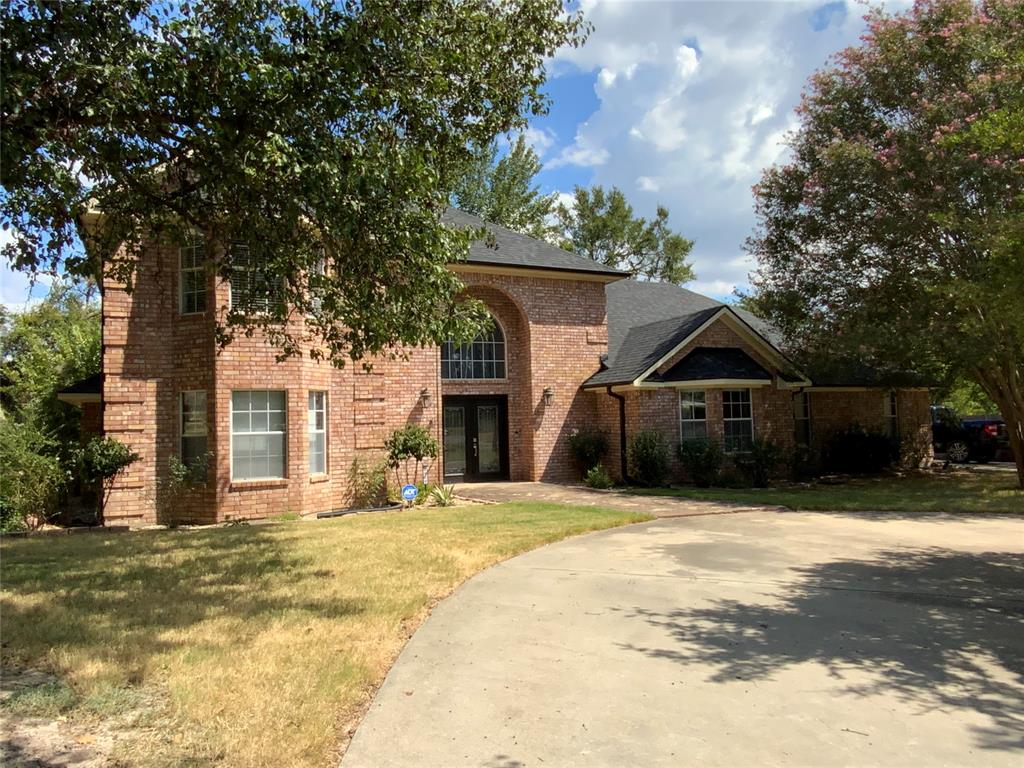 2020 Arbor Bend Road Bonham, TX 75418 - Photo 2 of 30 Brick facade residence featuring a prominent arched entry, dark shingled roof, and a paved driveway