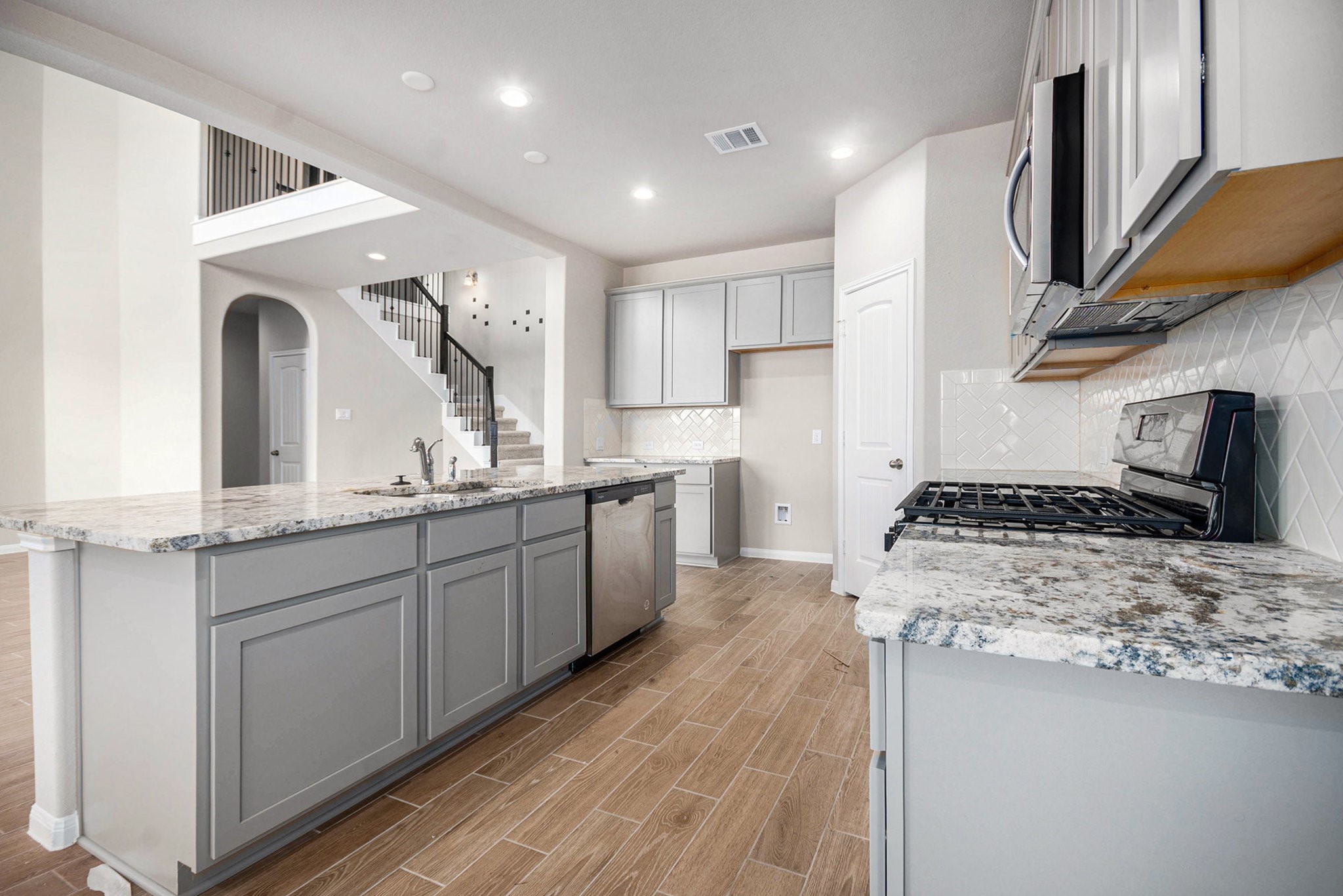 25 Carmel Drive Manvel, TX 77578 - Photo 17 of 50 a kitchen with stainless steel appliances granite countertop a sink a stove and a wooden floors