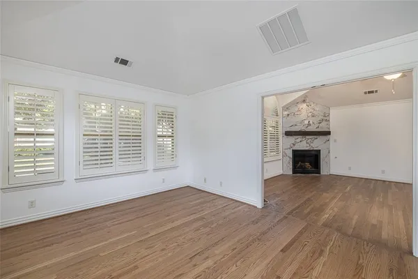a view of an empty room with wooden floor fireplace and a window