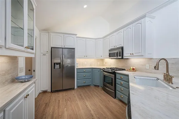 a kitchen with stainless steel appliances granite countertop white cabinets a refrigerator a sink a stove and a refrigerator