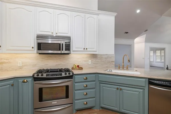a kitchen with cabinets stainless steel appliances and a counter space