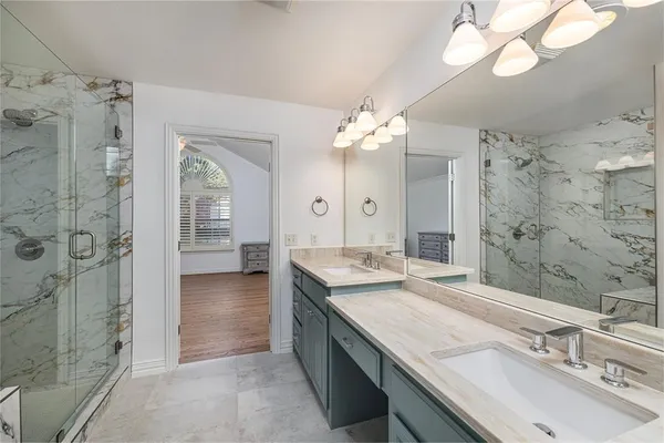 a bathroom with a granite countertop double vanity sink mirror and shower