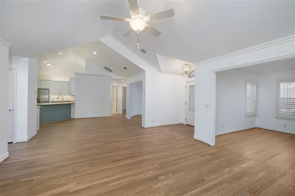 a view of empty room with wooden floor and ceiling fan