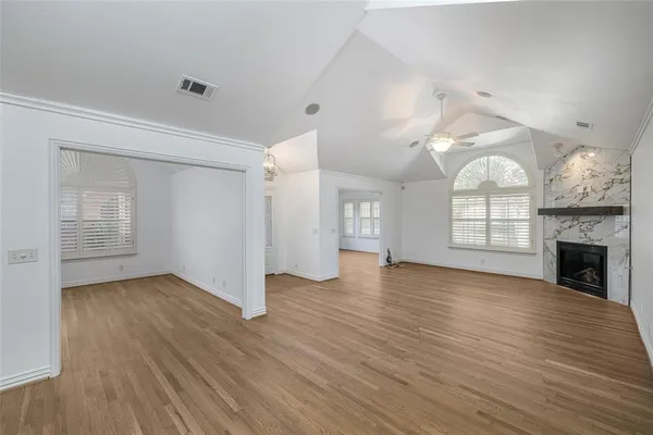 an empty room with wooden floor fireplace and windows