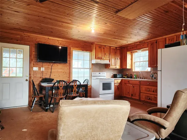 a living room with furniture a flat screen tv and kitchen view