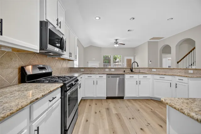 a kitchen with granite countertop stainless steel appliances a sink stove top oven and cabinets