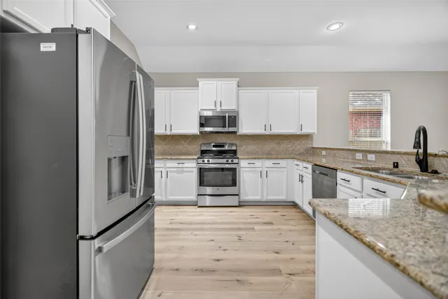 a kitchen with granite countertop white cabinets and stainless steel appliances