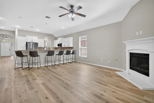 a view of an empty room with kitchen and fireplace