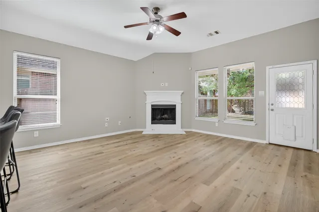 a view of an empty room with a window and wooden floor