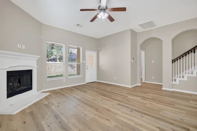 a view of an empty room with wooden floor fireplace and a window