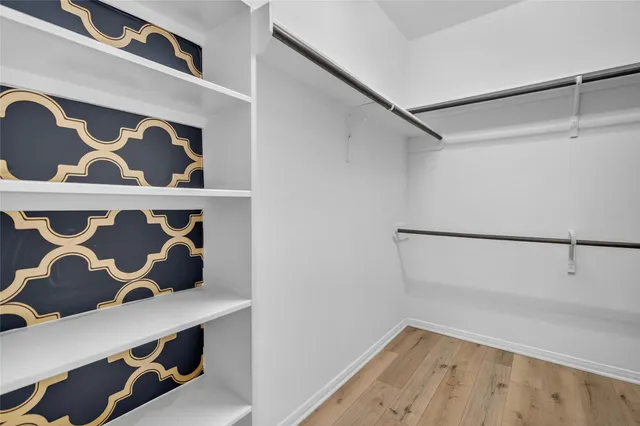 a view of walk in closet with clothes and shoes