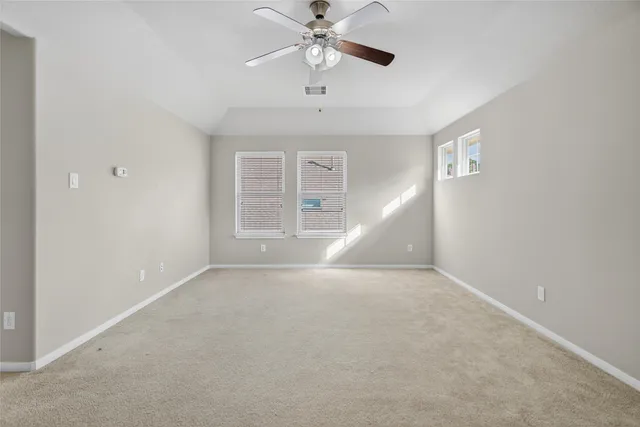 an empty room with ceiling fan and window