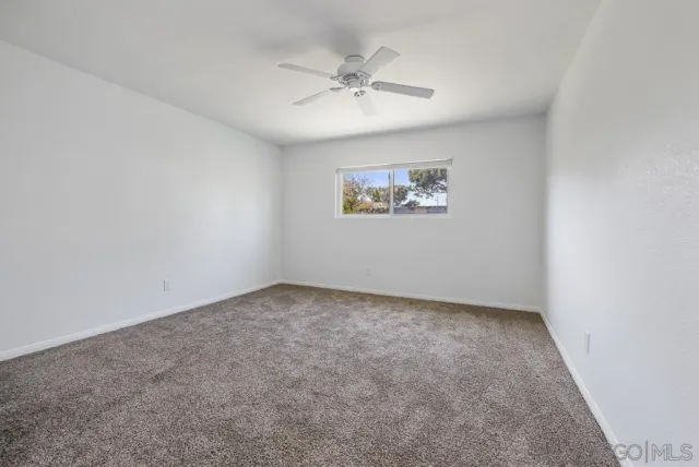 an empty room with a ceiling fan and window