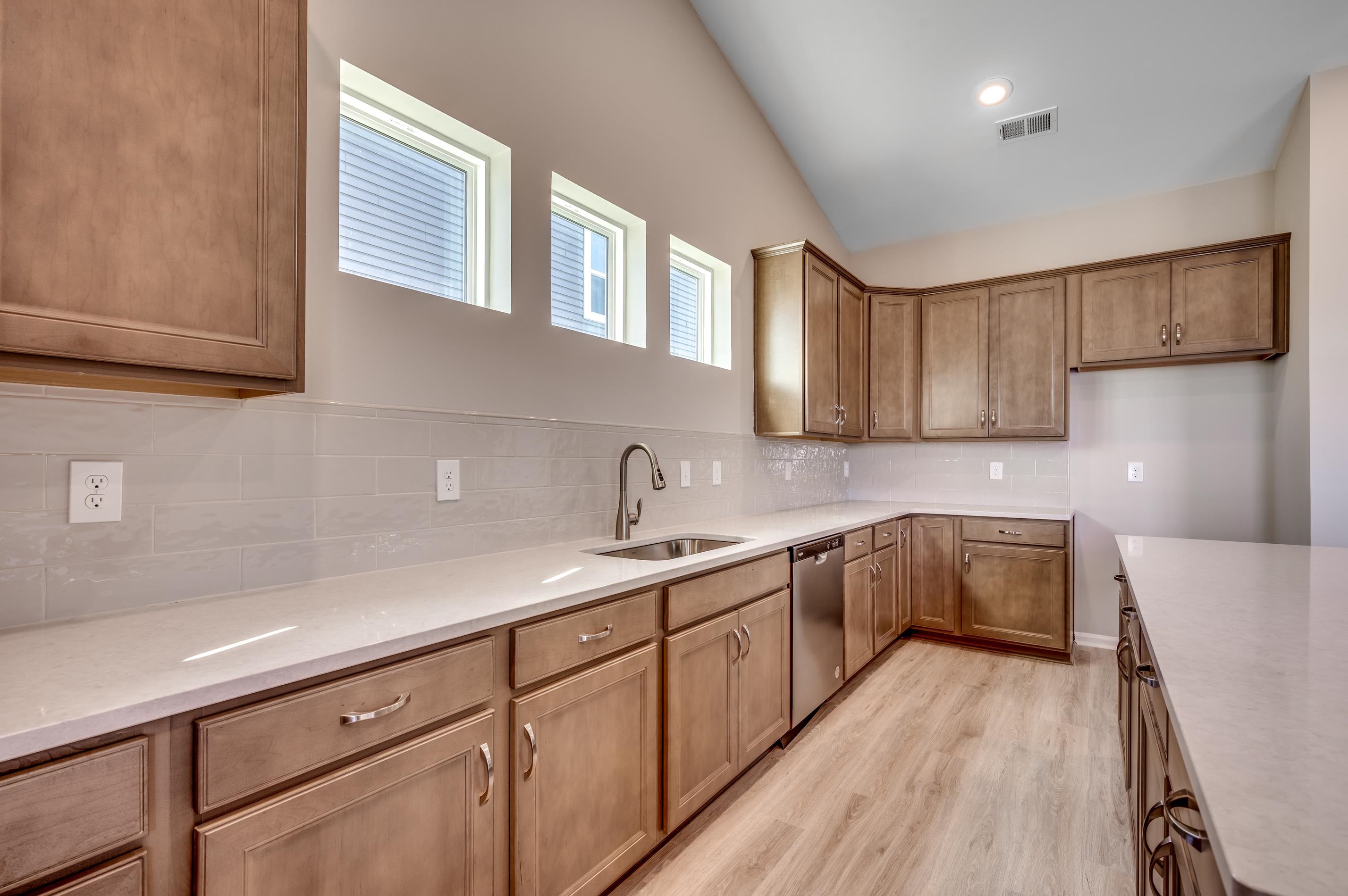 3 Buckingham Drive Loris, SC 29569 - Photo 6 of 7 Kitchen with brown cabinetry, light stone countertops, decorative backsplash, stainless steel dishwasher, and light wood-type flooring