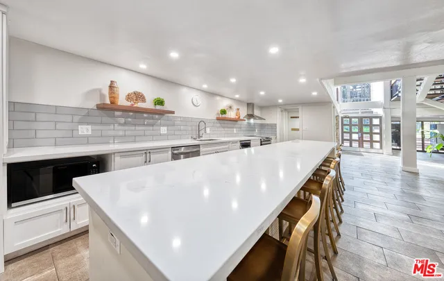 a kitchen with stainless steel appliances kitchen island a large counter top and a wooden floors