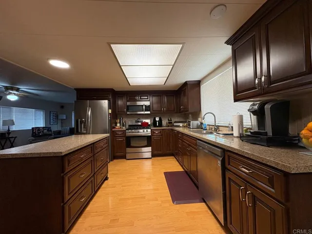 a large kitchen with stainless steel appliances wooden cabinets a stove top oven a sink and dishwasher