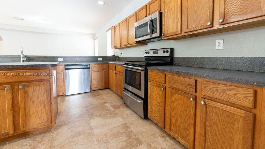 13962 Southwest 278th Street Homestead, FL 33032 - Photo 11 of 45 a kitchen with stainless steel appliances granite countertop a refrigerator a stove top oven and a sink with granite countertops