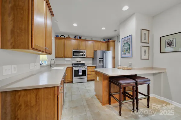 a kitchen with stainless steel appliances a stove a sink a microwave a refrigerator and cabinets