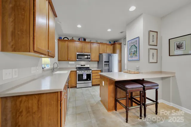 a kitchen with stainless steel appliances a stove a sink a microwave a refrigerator and cabinets