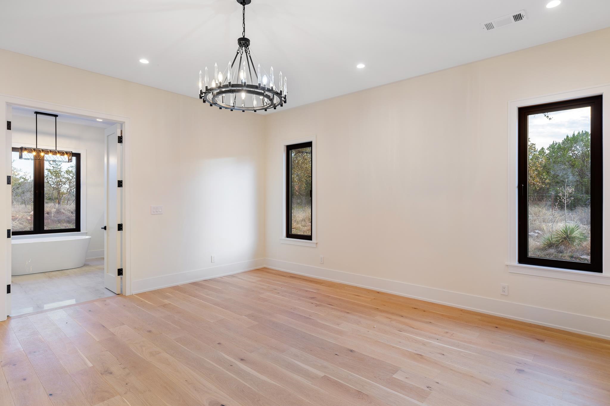 6425 Ranch Road 962 West Round Mountain, TX 78663 - Photo 13 of 30 a view of an empty room with wooden floor and a chandelier