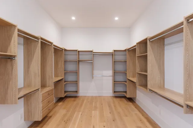 a view of walk in closet with wooden floor and cabinets