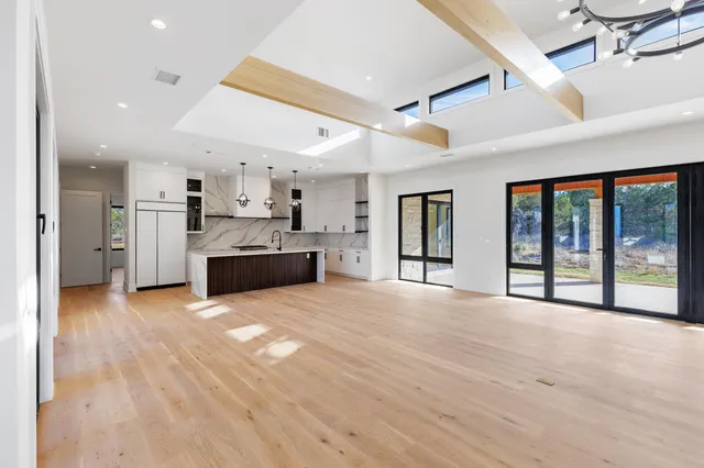 a view of an empty room with kitchen and a window